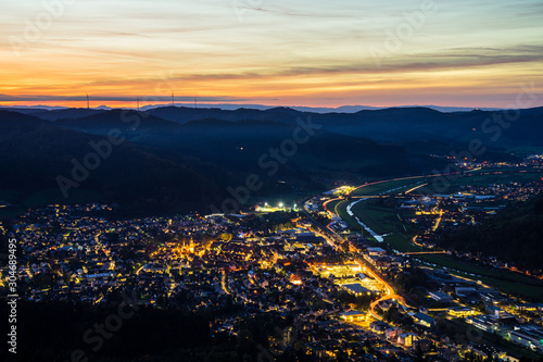 Germany, Black forest village skyline of haslach im kinzigtal houses, streets, cityscape illuminated by night, aerial view from above with red sky, a perfect nature landscape