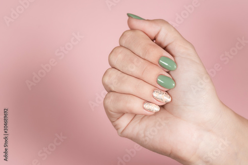 Closeup top view of one beautiful perfect manicured female hand isolated on pink pastel background. Fingernails with trendy two colors naildesign decorated with silver stamping on beige nails. 