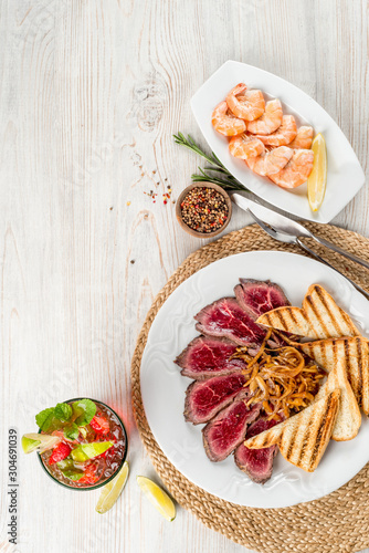 Roast beef with shrimp and drink on a wooden background
