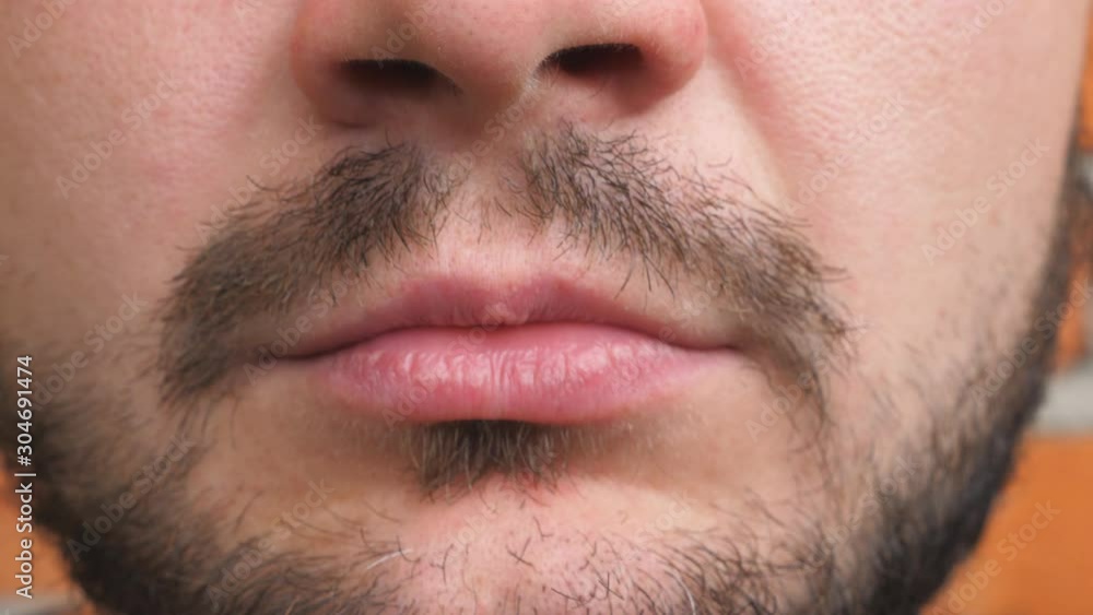 Close up lips of young bearded man. Detail view on closed male mouth. Portrait of handsome guy with serious and confident expression on the face. Front view Close up lips of young bearded man. Detail view on closed male mouth. Portrait of handsome guy with serious and confident expression on the face. Front view