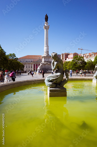 Lisbon, Portugal - July, 23rd, 2018 : Rossio square. South fountain, Column of Pedro IV and the Maria II national theatre in background.
