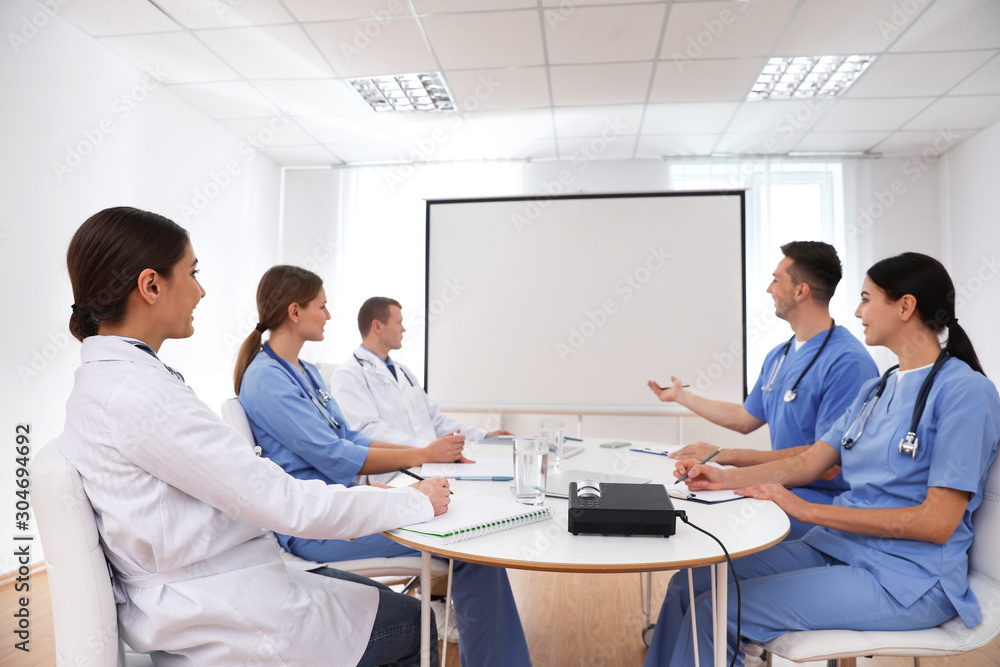 Team of doctors using video projector during conference indoors Team of doctors using video projector during conference indoors