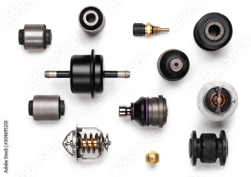Studio photography - a lot of automotive parts: silent blocks, thermostats, filter, sensors, ball bearings, lie in straight rows on a flat surface isolated on a white background.