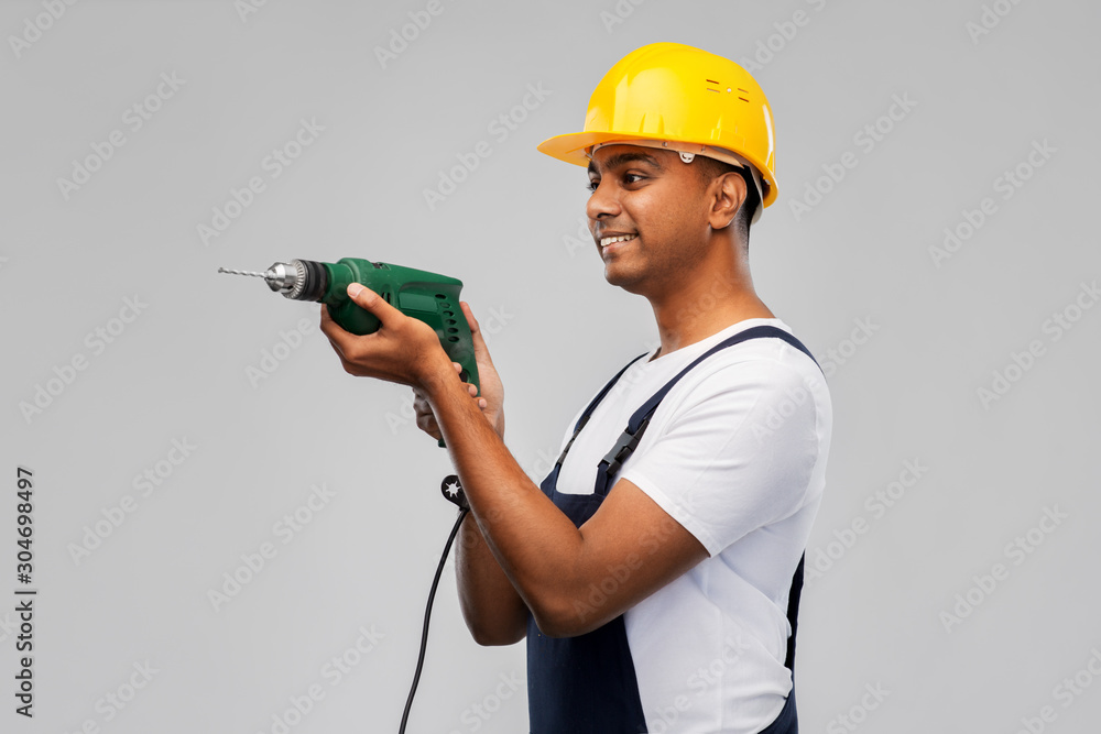 profession, construction and building - happy smiling indian worker or builder in helmet with electric drill or perforator over grey background profession, construction and building - happy smiling indian worker or builder in helmet with electric drill or perforator over grey background