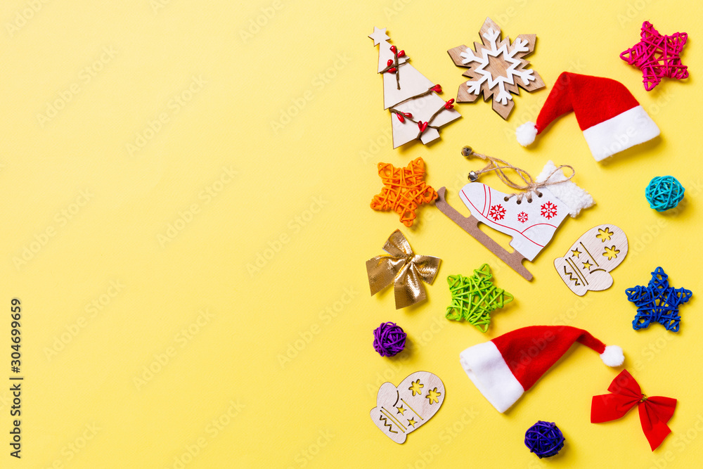 Top view of Christmas decorations and Santa hats on yellow background. Happy holiday concept with copy space
