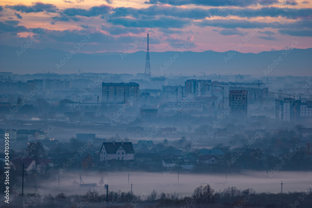 Fototapeta premium Sunset in the evening over the city in the fog