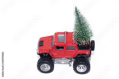 Red car carries a Christmas tree in the trunk . Toys. Christmas tree. New year and Christmas.