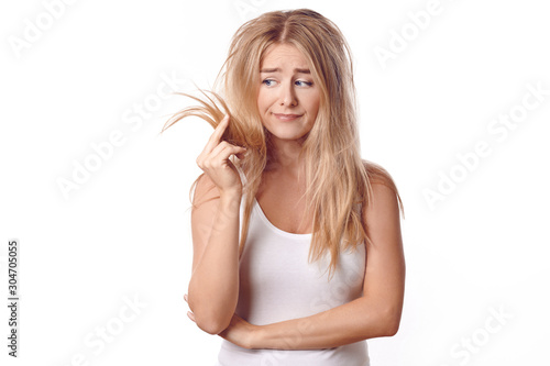 фотографія Pretty young woman having a bad hair day standing looking dejectedly at the dry