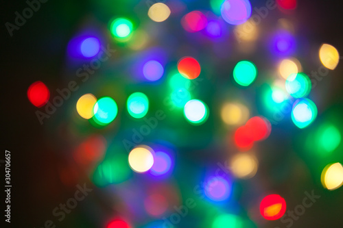 Abstract Christmas background. Photo of glowing blurry lights. Decoration garland with multi-colored flickering lights