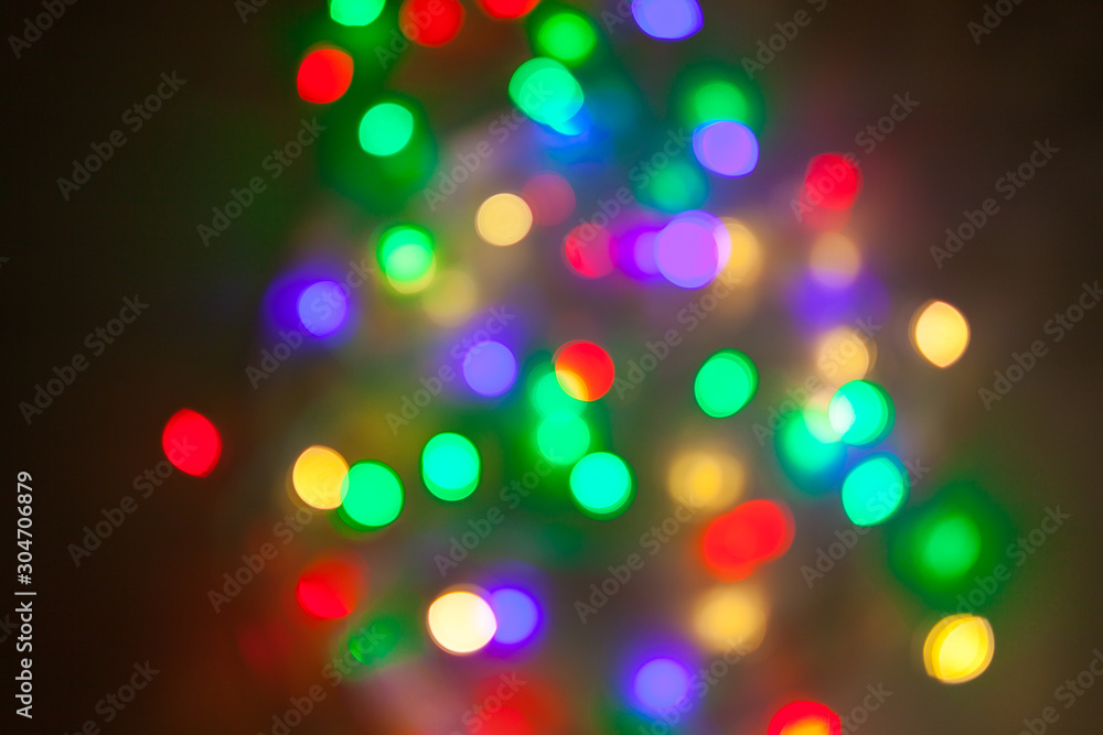 Abstract Christmas background. Photo of glowing blurry lights. Decoration garland with multi-colored flickering lights