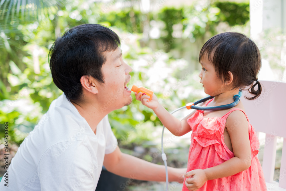 Asian father and daughter playing together with happy and funny moment, they playing a role of doctor and patient, concept of learning by playing for toddler development. Asian father and daughter playing together with happy and funny moment, they playing a role of doctor and patient, concept of learning by playing for toddler development.