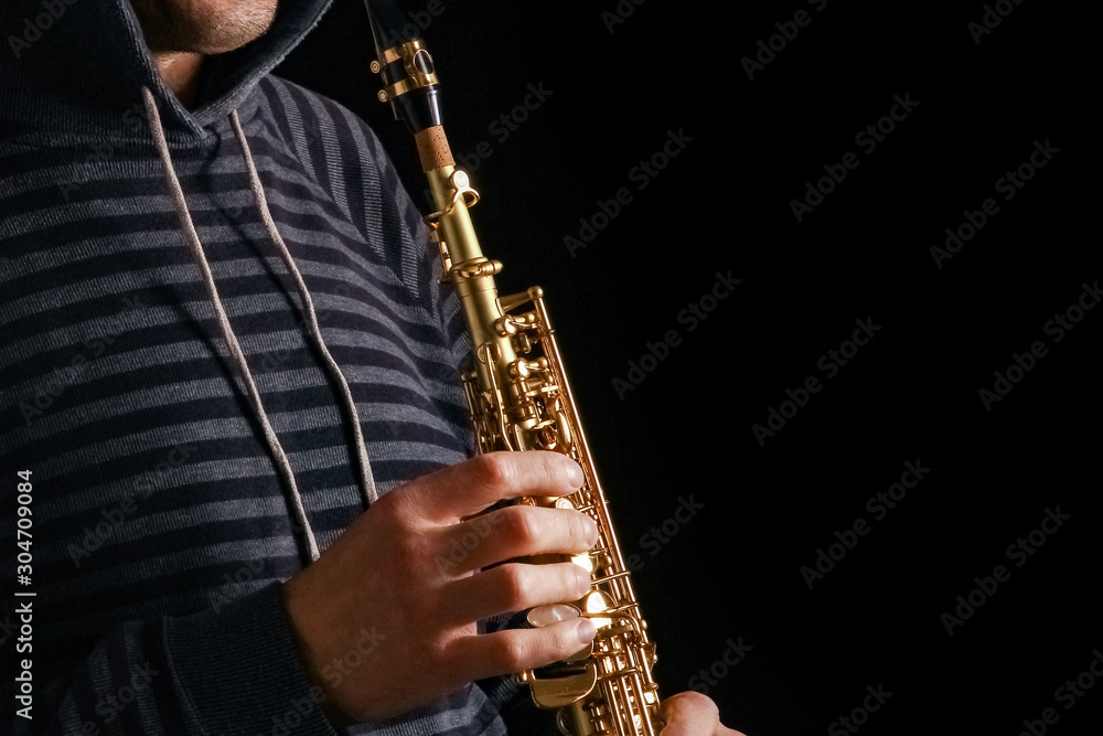 Obraz premium soprano saxophone in the hands of a guy on a black background