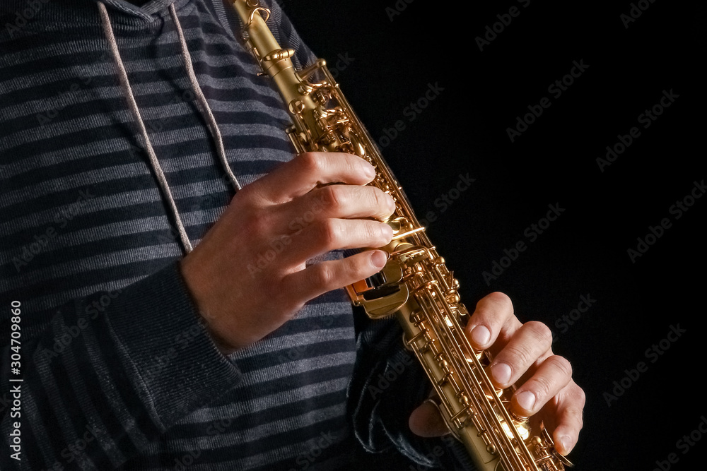 Fototapeta premium soprano saxophone in the hands of a guy on a black background