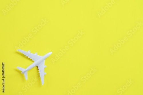 Miniature toy airplane white on yellow background.