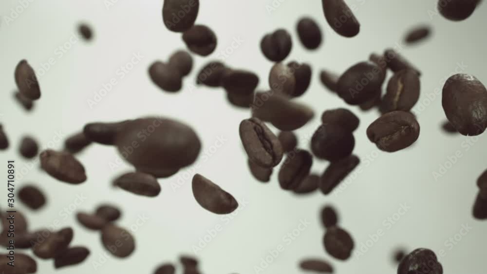 Roasted coffee beans fly up and spin on a white background Roasted coffee beans fly up and spin on a white background