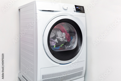 Electric dryer with clothes inside in the laundry room photo