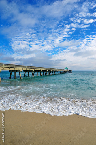 Seashore landscape with fishing pier with beach and waves in Atlantic Ocean in Florida