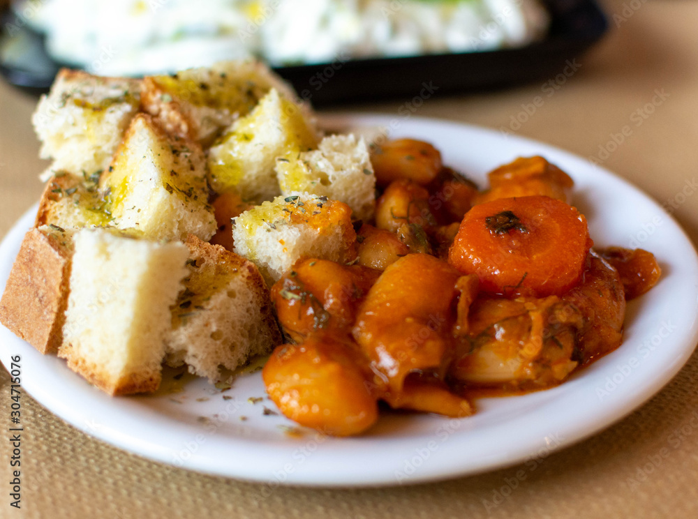 Greek food, cooked white beans with carrot and tomatoes served with roasted with olive oil and herbs bread Greek food, cooked white beans with carrot and tomatoes served with roasted with olive oil and herbs bread