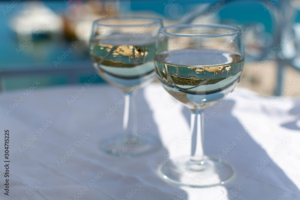 White wine served outside on balcony on glass table with sea view White wine served outside on balcony on glass table with sea view