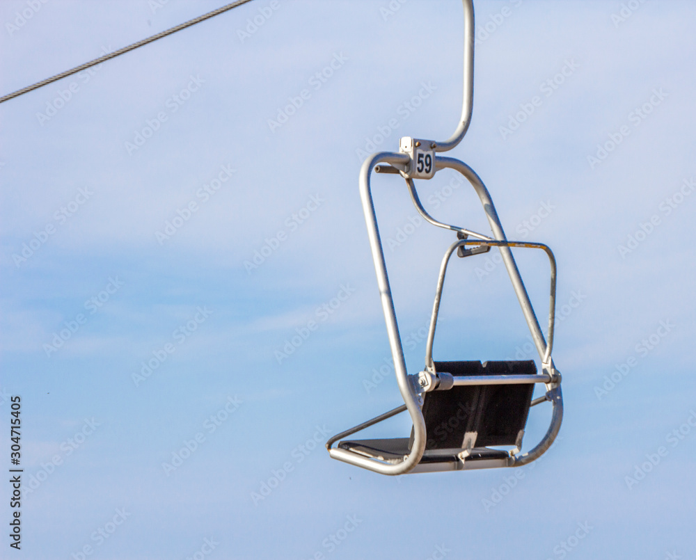 Chair ski lift with skiers over blue sky in the evening