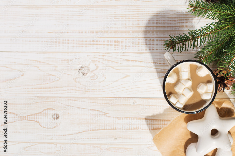 Hot Christmas drink with marshmallows in an iron mug and gingerbread cookies, on a white table. New Year, holiday background, copy space. Hot Christmas drink with marshmallows in an iron mug and gingerbread cookies, on a white table. New Year, holiday background, copy space.