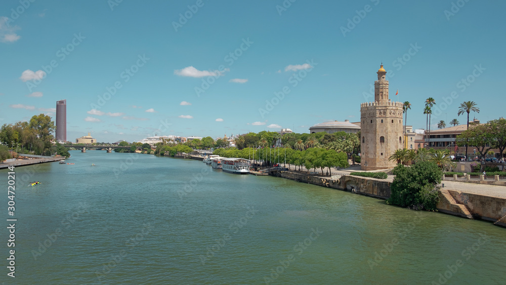 Views of the city from the bridge Puente San Telmo over Guadalquivir river towards watchtower Torre del Oro, Triana bridge and neighborhood and Cajasol Tower, in Seville, Andalusia, Spain