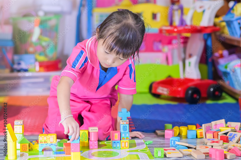 Fototapeta premium Asian little girl child playing in space toys for children develop in preschool, also known as nursery school