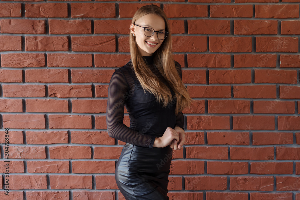 Elegant smiling woman in eyeglasses on a brick wall background Elegant smiling woman in eyeglasses on a brick wall background