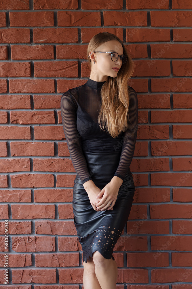 Elegant smiling woman in eyeglasses on a brick wall background Elegant smiling woman in eyeglasses on a brick wall background