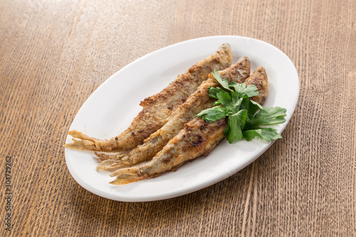 Seafood fried fish in batter on white plate isolated on wooden table