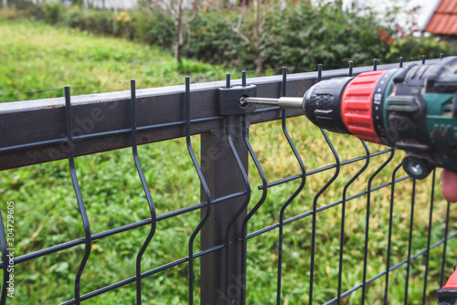 Fototapeta Man hand Screwing grating wire industrial fence panels