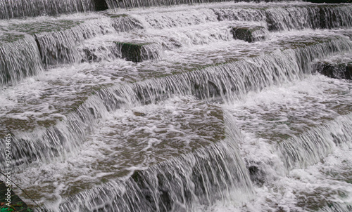Water Cascading over Weir Steps on canal slipway showing blur blurred motion and freeze frame of water droplets for background tectures and layer effects photo
