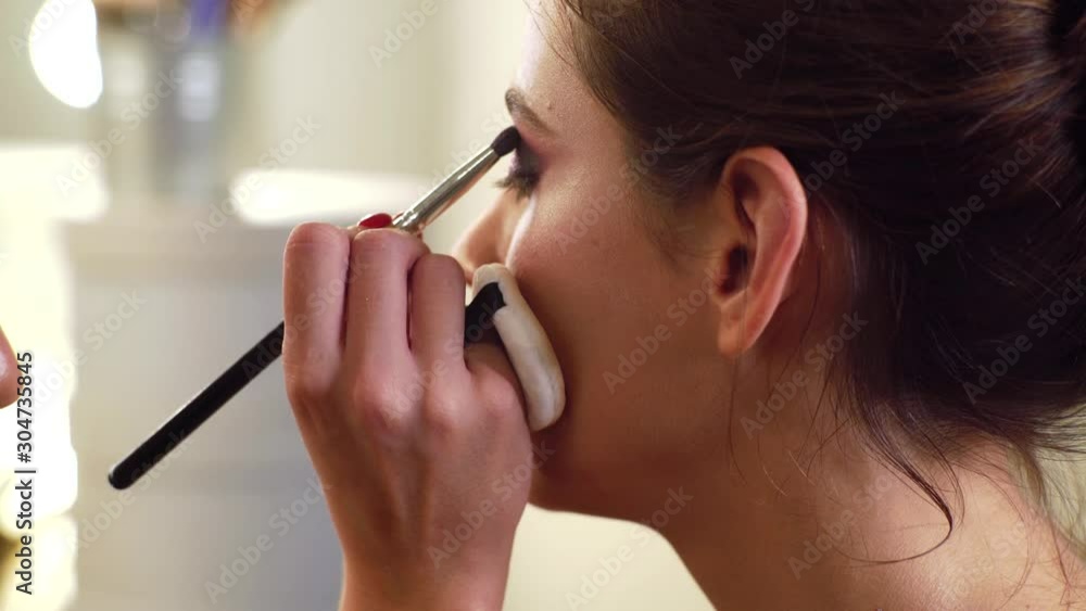 Eyeshadow applying - makeup for eyes closeup. Beautiful woman make-up. Make up in process.