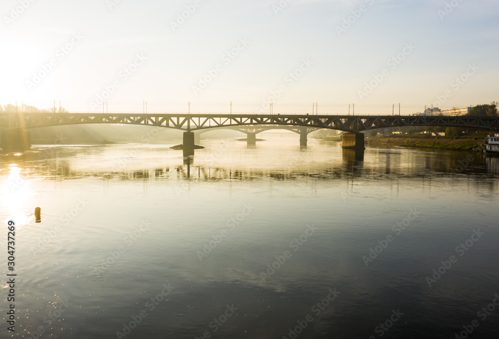 Drone flies to a railway bridge passing over the Vistula River in Warsaw. Poland. 04. October. 2019.  Aerial view of a bridge in the fog in the early morning at sunrise.