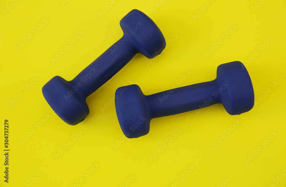 blue dumbbells isolated on a yellow background. The concept of fitness, gym and healthy lifestyle. Top view. Flat lay. Copy space for text. Background, pattern, banner. blue dumbbells isolated on a yellow background. The concept of fitness, gym and healthy lifestyle. Top view. Flat lay. Copy space for text. Background, pattern, banner.