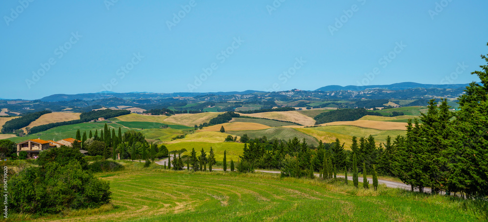 Fototapeta premium Beautiful view in Tuscany, Italy. Rural landscape. Countryside hills and meadows, green and yellow fields and sky. Beautiful world.