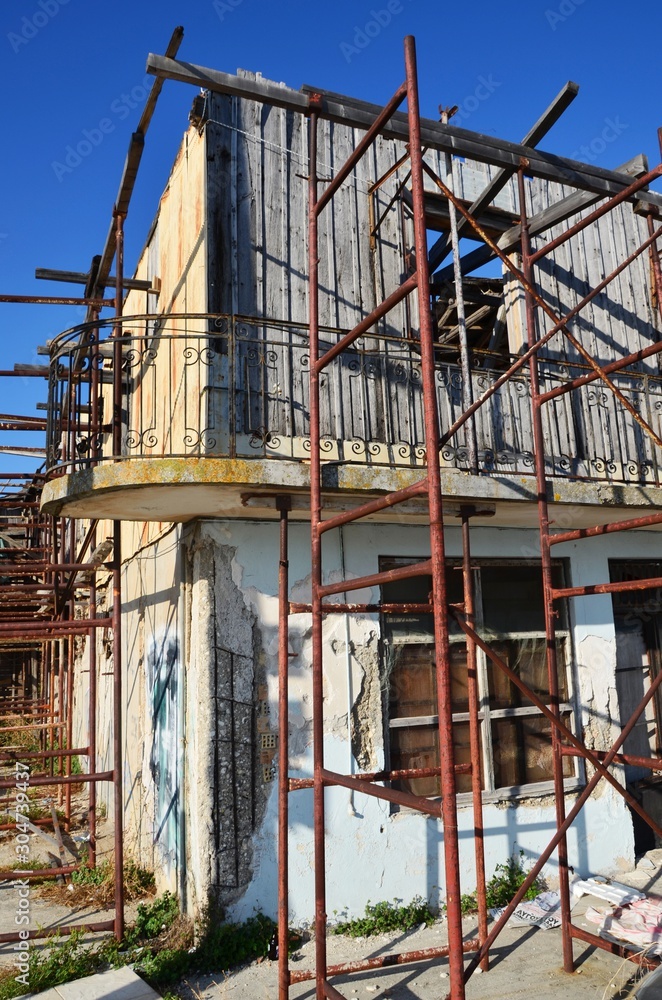 Lefkada, Lefkada Island, Greece. 10/22/2019. old ruined house without windows and doors, on the street of European town. building for reconstruction, with scaffolding. cityscape, street without people Lefkada, Lefkada Island, Greece. 10/22/2019. old ruined house without windows and doors, on the street of European town. building for reconstruction, with scaffolding. cityscape, street without people