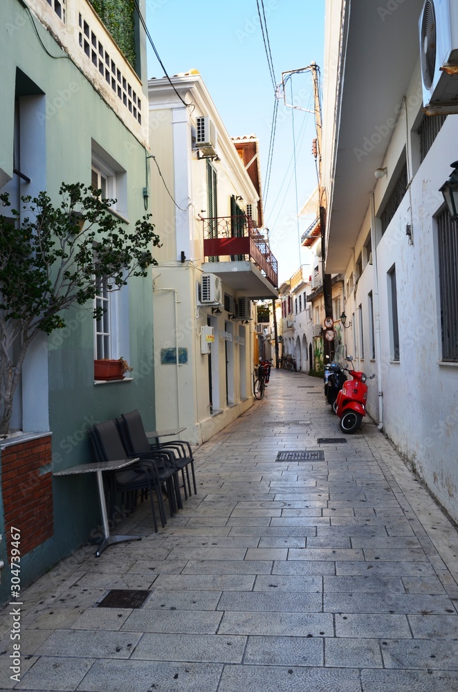 Obraz premium Lefkada, Lefkada Island, Greece. 10/22/2019. narrow streets, old houses, windows, doors, balconies, green plants, bright flowers in a European town on the island. cityscape, street without people