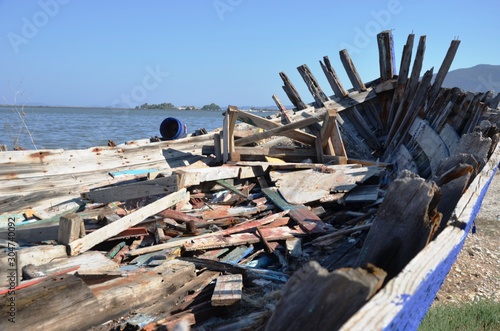 Lefkada, Lefkada Island, Greece. 10/22/2019. garbage and trash inside broken old wooden ship of blue and white color, fishing boat standing on land in port © Lucy_Kozyra