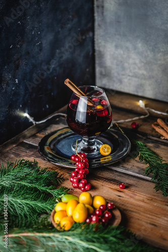 mulled wine in glasses with anise, citrus and berries on brown wooden table, Christmas decoration, copy space