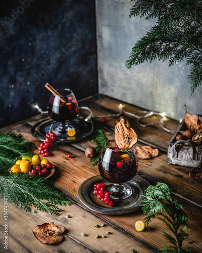 mulled wine in glasses with anise, citrus and berries on brown wooden table, Christmas decoration, copy space