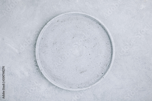 Empty round stone plate on gray concrete background, top view