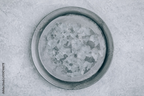 Empty round metal plate on gray concrete background, top view,