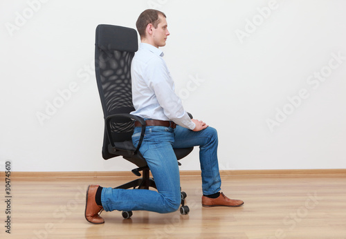 Caucasian man stretching leg at the office chair