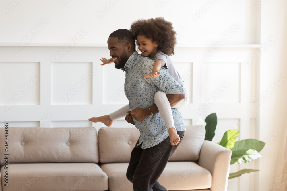 Obraz premium Happy biracial daughter piggyback play with young dad