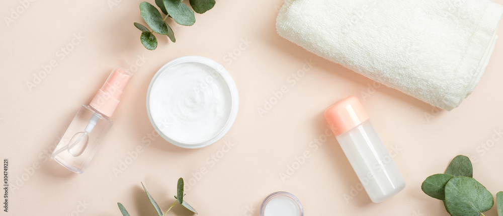Jar of cream and organic spa cosmetic product on beige background with eucalyptus leaves and towel. Natural organic beauty spa product concept.