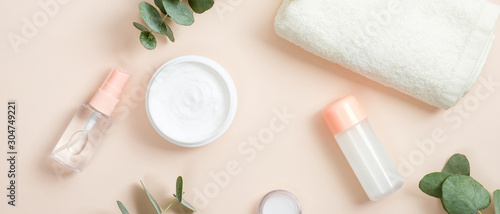 Jar of cream and organic spa cosmetic product on beige background with eucalyptus leaves and towel. Natural organic beauty spa product concept.