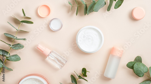 Flat lay composition with natural organic cosmetic products on beige background. Top view hand cream in jar, essential oil, skin lotion and eucalyptus leaves. Natural organic beauty product concept photo