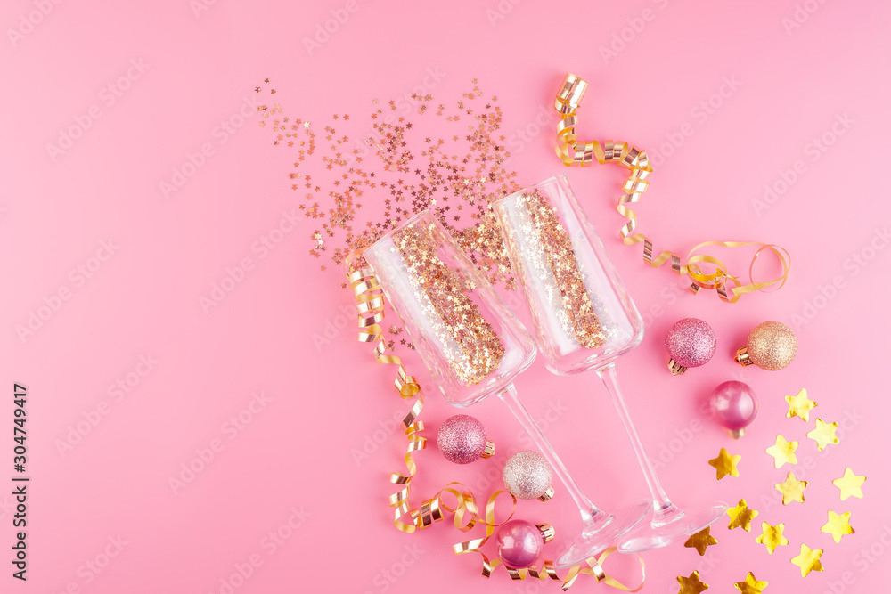 Two glasses of champagne filled with gold stars confetti on a pink pastel background