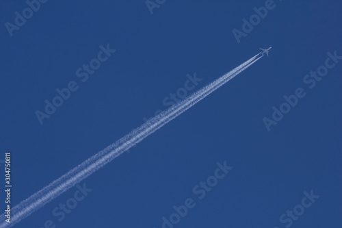 An aircraft with contrail flying diagonally across the frame